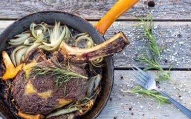 Entrecote kjøttstykke liggende i steikepanne med urter.